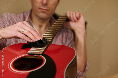 Fotografie Man Cleaning Acoustic Guitar Fretboard During String Maintenance And Repair