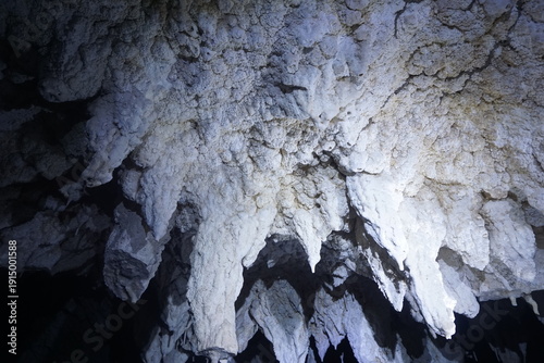 Photos Illuminated stalactites in a dark cave formation.