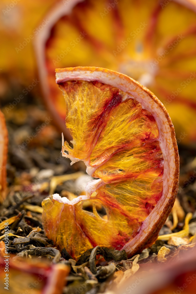 Fototapeta premium tea with added flavors and pieces of fruit and cut red oranges, bright large dry slices of blood red orange and green tea with pieces of fruit, close up