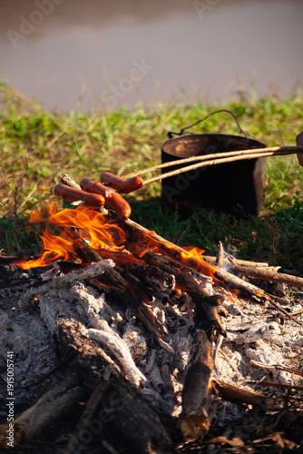 Roast sausages over a campfire