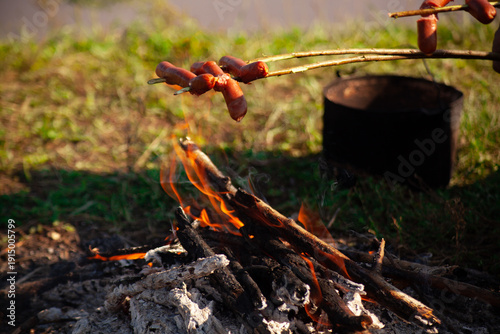 Roast sausages over a campfire