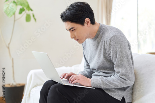 Foto 猫背でパソコン操作をするアジア人男性