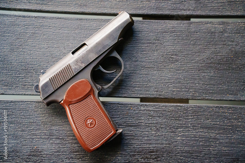 Small handgun resting on dark wooden surface during the day