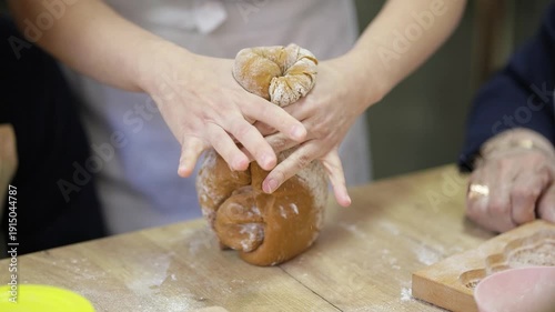 Women's hands knead the dough and tear off small pieces from it. A soft, wandering focus