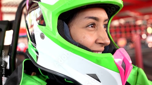 Thrilled young woman driving a go kart on an indoor racetrack