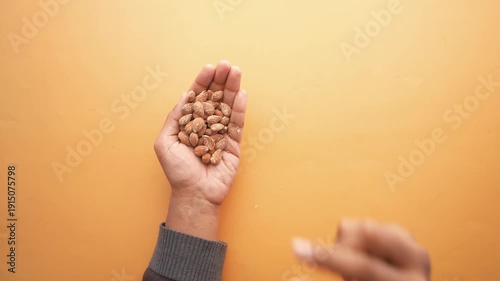 A person selecting and picking out individual almonds from a handful, showcasing healthy eating and snack choices