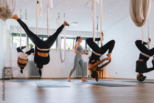 Aerial yoga class practicing poses in modern indoor studio