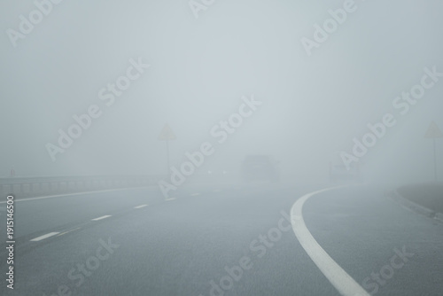 Empty road curve in dense fog with low visibility and copy space