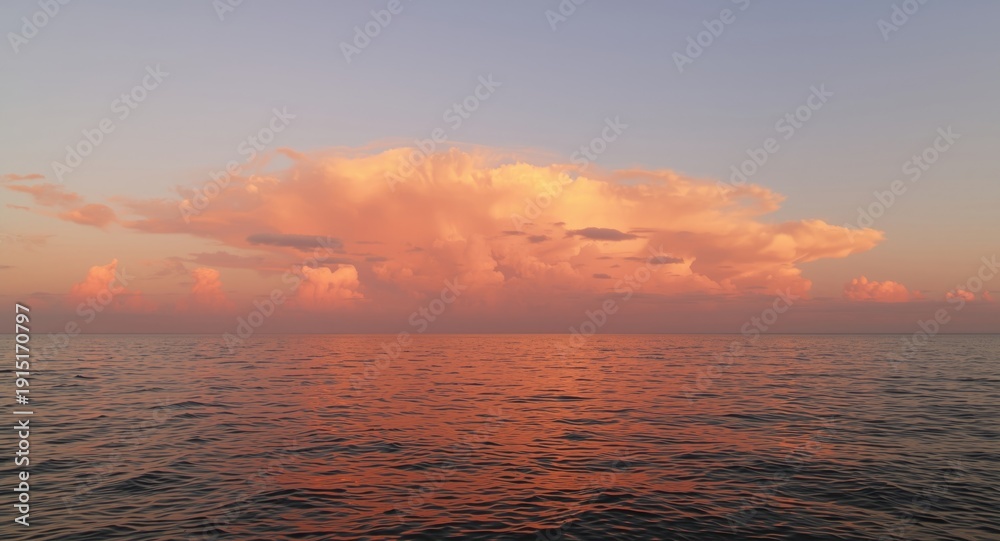 Fototapeta premium Peaceful sunset scene featuring glowing salmon pink clouds over ocean