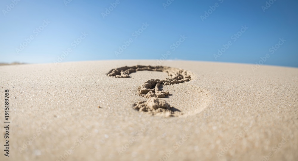 Obraz premium A question mark manually written in sand under bright natural sunlight