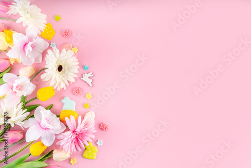 Beautiful spring flowers bouquet with Easter decorations on pink background. Easter holiday flat lay with eggs, rabbits and springtime flowers. Greeting card background with copy space