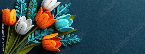 Un bouquet de tulipes en feutrine blanche, orange et cyan sur fond texturé bleu foncé, vue panoramique en gros plan, image avec espace pour texte.