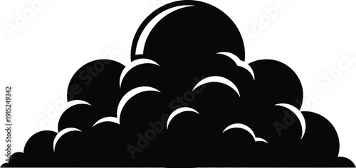 A black silhouette of a cumulus cloud formation at sunrise or sunset with the sun peeking through