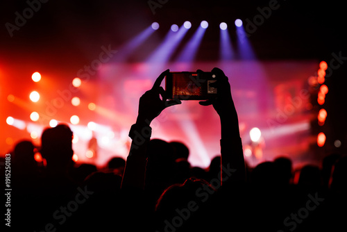 Person recording live concert performance with horizontal smartphone