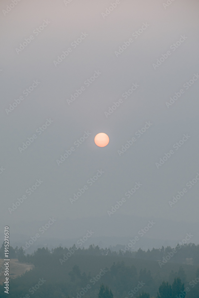 Obraz premium Orange sun partially obscured by thick wildfire smoke in southern Chile.