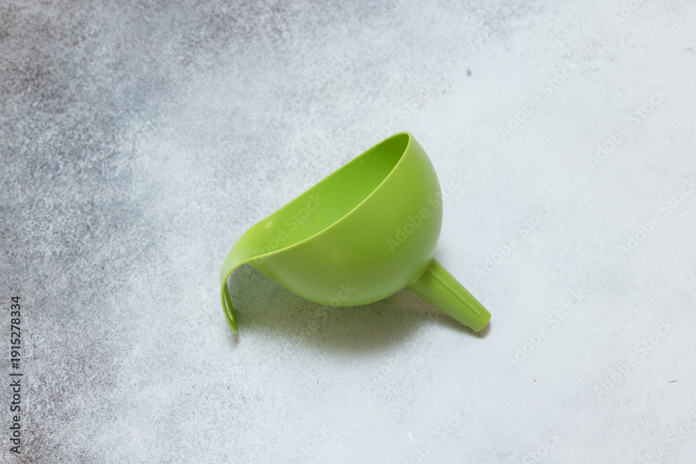 Naklejka premium Green plastic funnel kitchen tool warm closeup