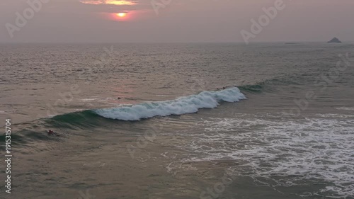 Beautiful sunset surf session at Naomi Beach. Surfers floating and catching waves in warm golden light, calm ocean, and scenic tropical horizon. Ideal footage for vacation, freedom, extreme sports, an