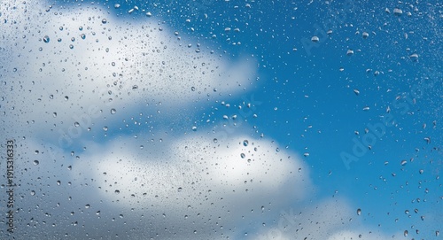 Clear liquid drops on frosted window pane contrasted by vibrant blue sky