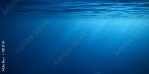 A wide angle underwater view captures sunlight rays piercing through the deep blue ocean surface as scuba diving light reflects across a natural liquid texture