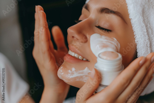 Beautiful young woman with closed eyes smiling while gently applying white facial cream to her cheek, beauty and skincare concept,  fresh glowing skin, daily self-care ritual