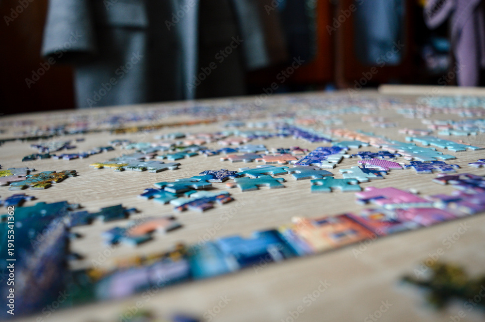 Fototapeta premium Jigsaw puzzle pieces on table, close up. Rising trend of analog hobbies, offline leisure, mindfulness activity, slow living, stress relief, cozy home entertainment and digital detox concept.