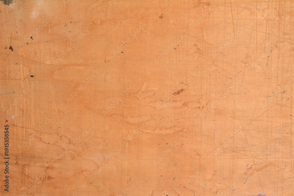 Obraz premium A close up view of a brown plywood surface with numerous scratches and light stains creating a worn industrial wood texture