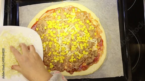Adorable young girl preparing homemade pizza by placing ingredients on fresh dough. 