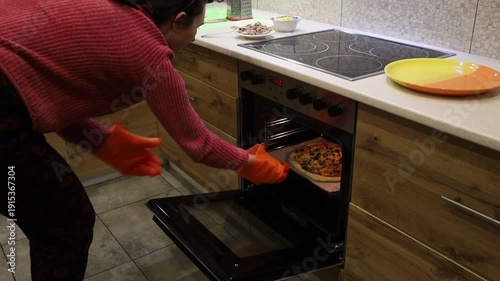 Young Woman Taking Out Homemade Pizza from the Oven