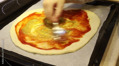 Adorable young girl preparing homemade pizza by placing ingredients on fresh dough.