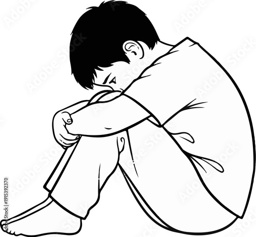 A boy sits curled up, head bowed, conveying feelings of sadness and isolation