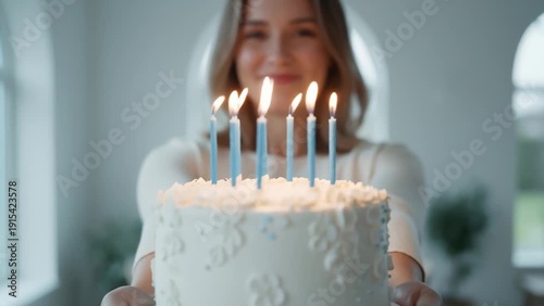 Young Woman Smiling Holding Birthday Cake With Lit Candles in Bright Modern Home, Close Up