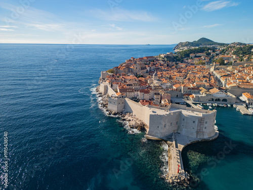 Epic Dubrovnik old town cityscape sunset aerial panorama. 
Cinematic drone bird's eye view of historic medieval city walls, 
orange roofs, luxury yachts harbour and blue Adriatic sea in Croatia.
