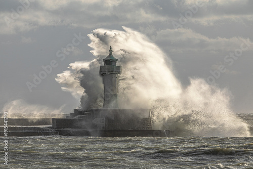 Leuchtturm Sassnitz im Wintersturm – gewaltige Wasserwand und Gischtfahne hinter dem vereisten Molenkopf, dramatisches Gegenlicht über der Ostsee auf Rügen