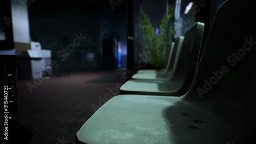 Fotografija Rows of empty chairs sit in a dark waiting area, surrounded by shadows and soft green plants