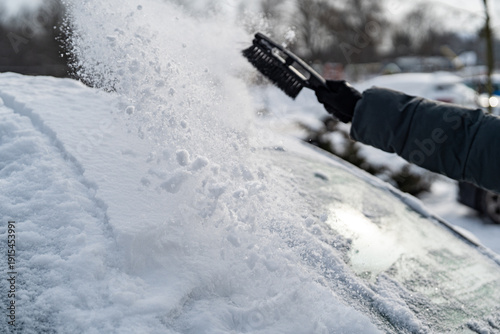 Scraping ice and snow from car windshield with plastic scraper on a cold winter day