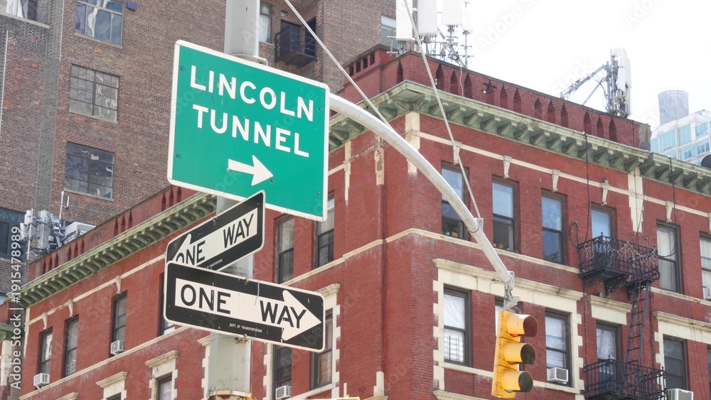 Obraz premium New York City Lincoln Tunnel street sign in Manhattan Midtown, United States. Urban road sign in american city, traffic sign in NYC. Red brick building architecture, Chelsea district near Hudson Yards
