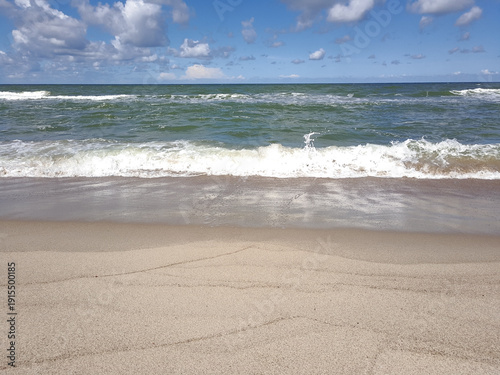 Baltic Sea coastline with turquoise water  white foam and cloudy blue sky