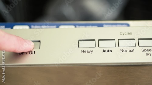 Finger pressing the dishwasher power on button
