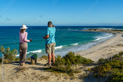 A retired couple enjoying the stunning coastal vista to Struis Point (Struispunt) and Saxon Reef from sea cliffs near Waenhuiskrans, Arniston. Serene Overberg moment, Western Cape, South Africa.