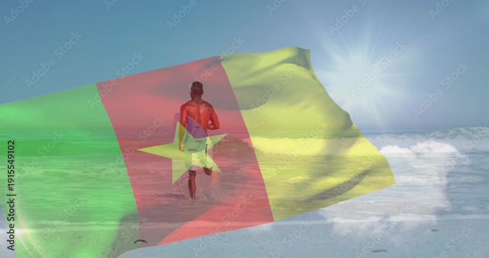 Fototapeta premium Walking surfer carrying surfboard and wearing swim trunks into shallow ocean at beach, flag overlay