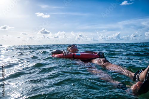 Foto A man is floating on a red life preserver in the ocean