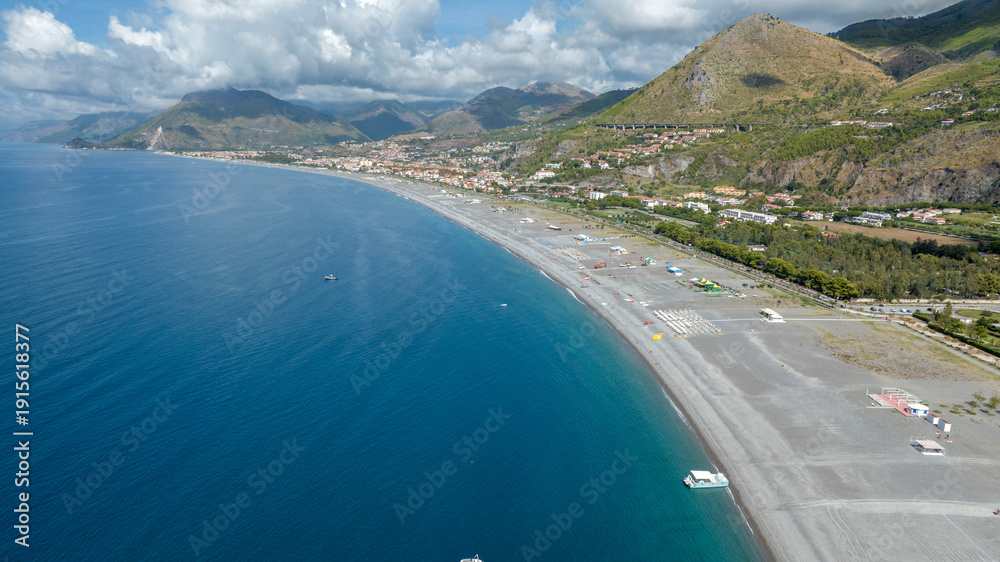 Obraz premium Aerial view of the long beach of Praia a Mare, located in the province of Cosenza, Calabria, southern Italy. Panorama of a vast grey pebble coastline meeting the deep blue Tyrrhenian sea.