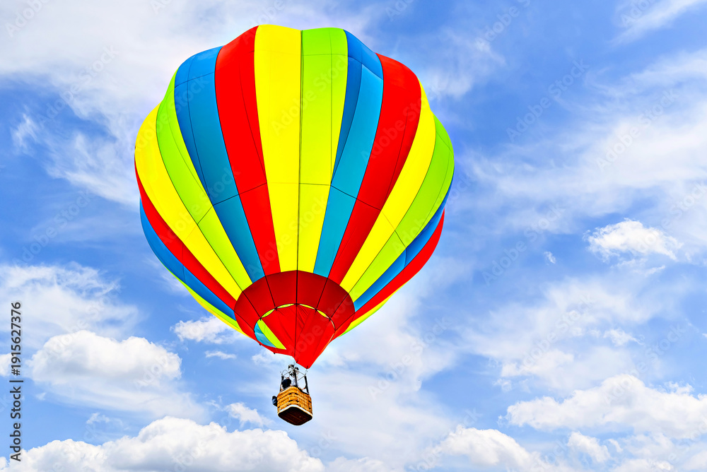 Obraz premium Colorful hot air balloon flying over blue sky with white clouds