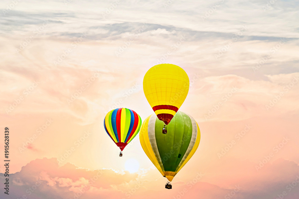 Obraz premium Colorful hot air balloon flying under orange sunset sky 
