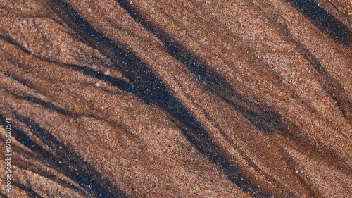 Magical with Black Sand Beaches on multicolored Hormuz Island, Iran. The dark sand from heavy minerals such as hematite, ilmenite, and magnetite, creating striking textures along the shoreline.