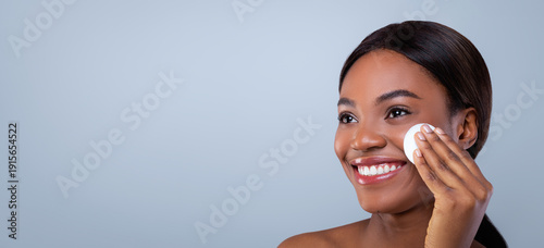 Foto A woman is using a cotton pad to apply skincare product on her face