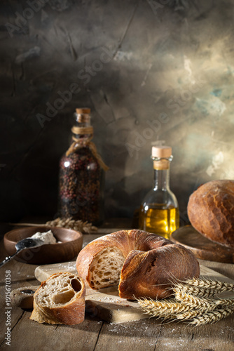 Fresh wheat bread and ears of wheat on a rustic table
