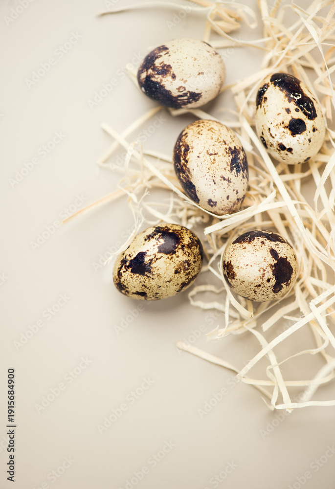 Fototapeta premium Quail eggs, breakfast, fresh quail eggs and straw on beige background. Easter border design, flat lay, top view. Healthy diet food concept. Vertical image 