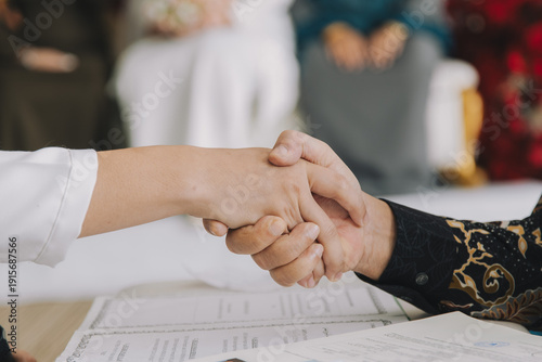 Groom Shaking Hands During Nikah Ceremony.A close-up of a groom's hand shaking the hand of the officiant or father (Wali) during the solemnization of marriage (Akad Nikah) in a Malay wedding.
