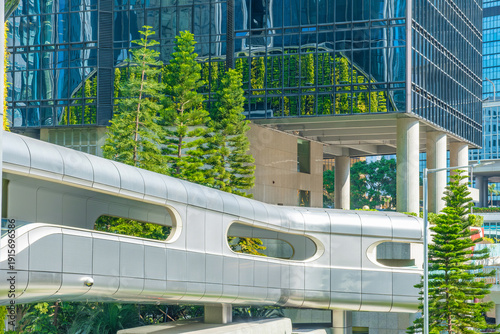 Canvas Print Futuristic pedestrian bridge with glass office buildings and urban greenery in Hong Kong city, China